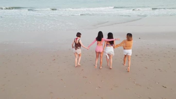 空中无人机的观点亚洲和印度青少年种族妇女在幸福行动中走在一起进入海滨海滩