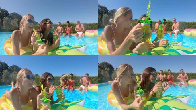 穿着泳装的年轻多民族朋友的真实照片是在五颜六色的充气设备上放松身心，并在阳光明媚的日子里一起在游泳池