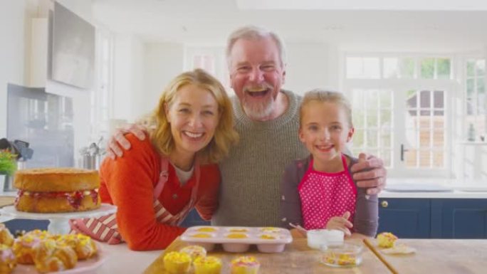 祖父母和孙女的肖像在厨房柜台上装饰自制蛋糕