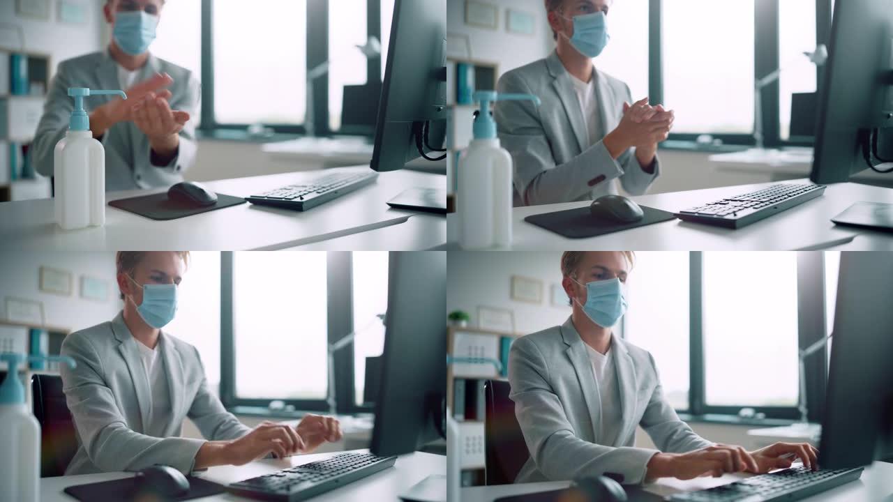 戴着防护口罩的英俊时尚年轻人在办公室的电脑上在办公桌前工作时使用洗手液。蓝眼睛金发年轻男性遵循健康和
