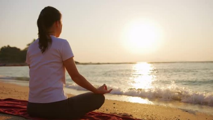 日落时坐在沙滩上做瑜伽的女人