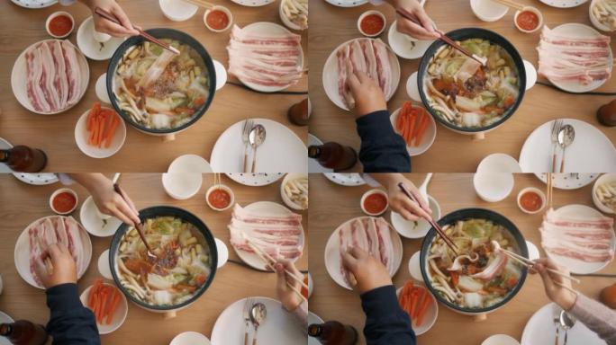 用筷子在火锅里做饭的手的俯视图。