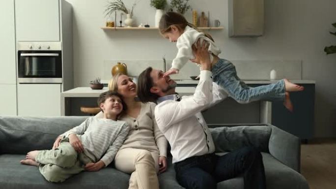 幸福的夫妇和顽皮的孩子坐在家里的沙发上