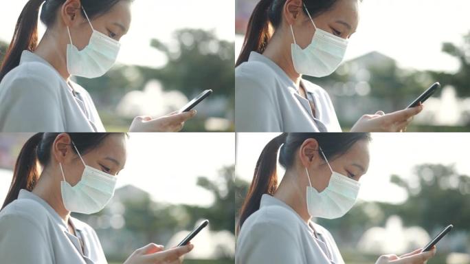 戴口罩使用智能手机的年轻亚洲妇女