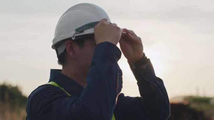 男性工程师在日落时戴上建筑头盔的慢动作特写