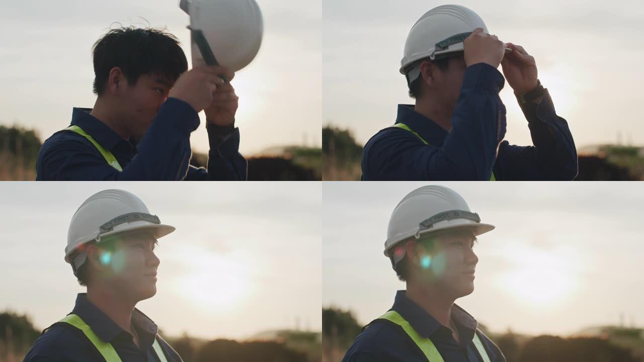 男性工程师在日落时戴上建筑头盔的慢动作特写