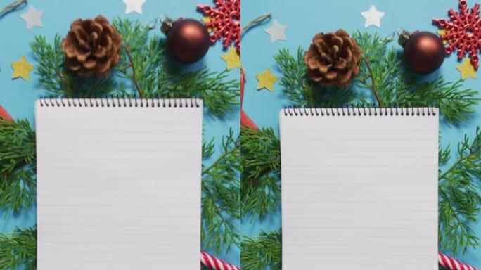蓝色背景上的圣诞节装饰品包围着笔记本的垂直头顶照片