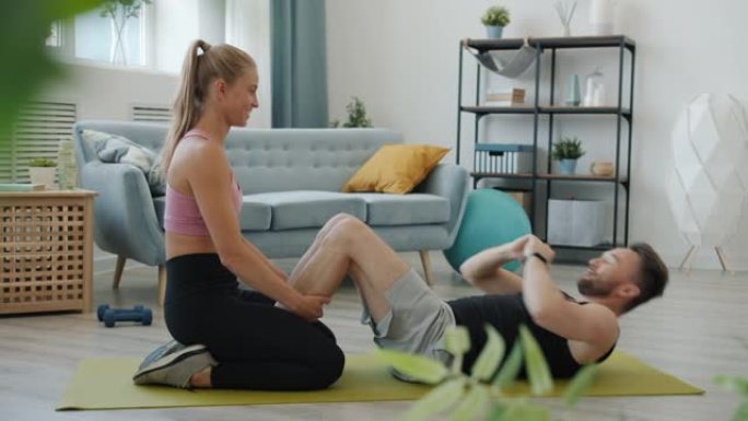 快乐年轻人的慢动作夫妇在公寓里一起训练在瑜伽垫上锻炼