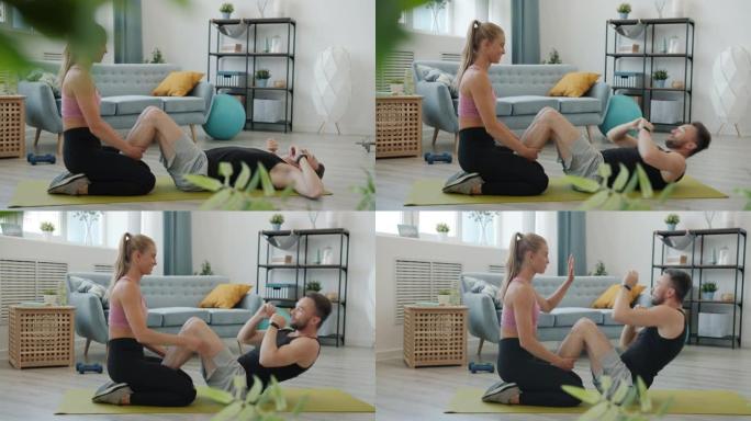 快乐年轻人的慢动作夫妇在公寓里一起训练在瑜伽垫上锻炼