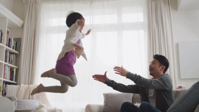 可爱的亚洲小女孩跳进父亲的怀抱快乐的爸爸轻轻地抓住他的女儿在家里享受和孩子玩耍的游戏4k