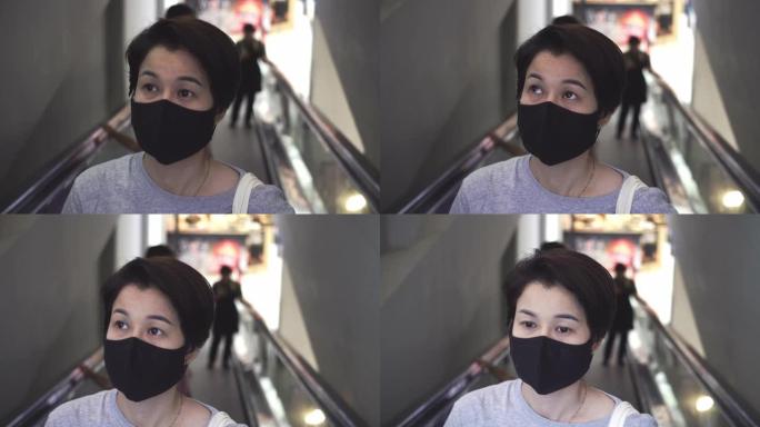 商场自动扶梯上戴防护面罩的亚洲女子