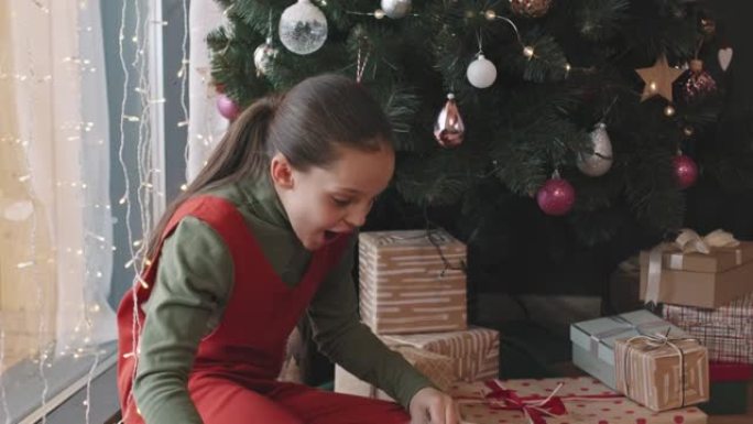 女孩打开圣诞礼物盒的包装