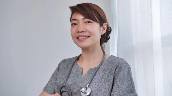 亚洲女医生肖像年龄38岁经验丰富的医生站在双臂交叉，微笑着直接看着相机，自信，友好，值得信赖，在医院