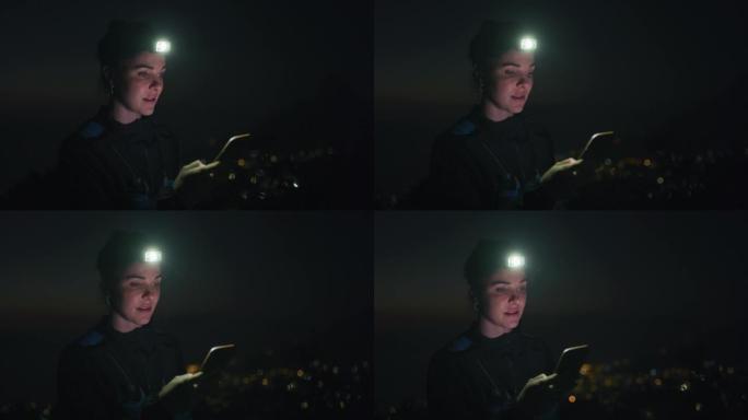 4k视频片段，一名妇女在夜间在户外时戴着头灯并使用手机