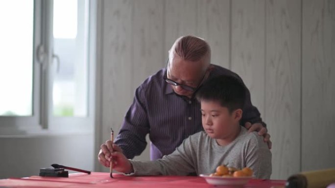 亚洲华裔小男孩向祖父学习中国书法