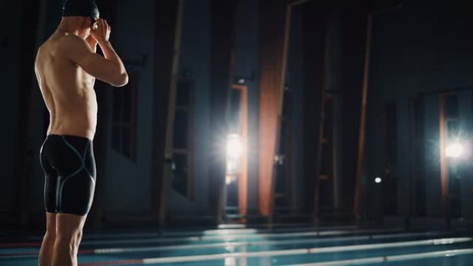 运动男游泳运动员从起跑线跳进游泳池。坚定的专业肌肉运动员赢得冠军。电影光、艺术色彩、慢动作、跟踪弧