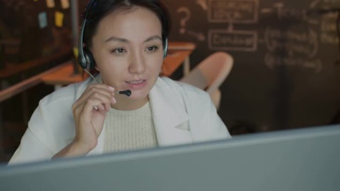 客户支持专家在黑暗的办公室接听电话并使用计算机