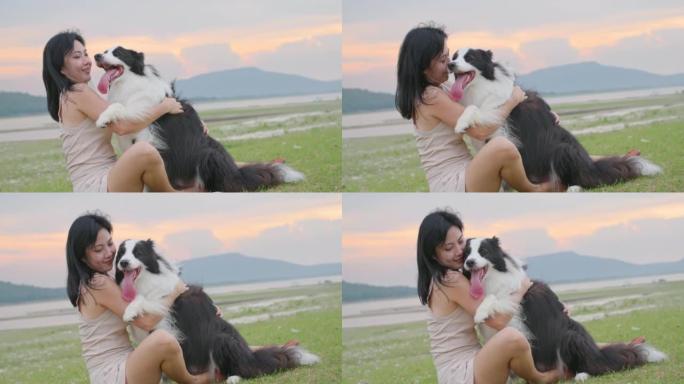 年轻的亚洲女人用爱拥抱和亲吻她可爱的朋友边境牧羊犬。