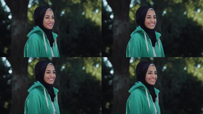 美丽的年轻阿拉伯女人微笑着绿色背景的特写肖像。带着头巾的快乐穆斯林女少年在公园里享受新鲜空气，照顾她