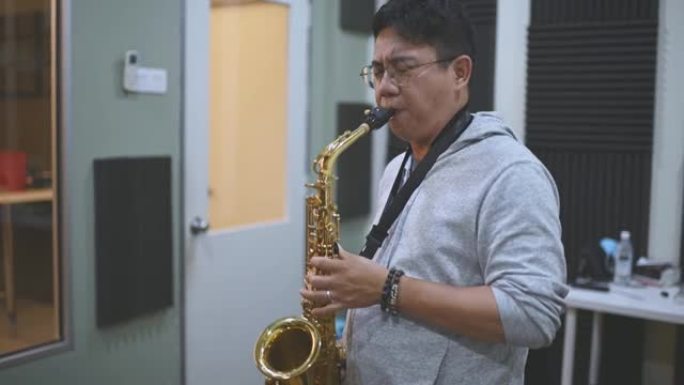 亚洲中国中年男子在音乐工作室课上学习乐器演奏萨克斯管