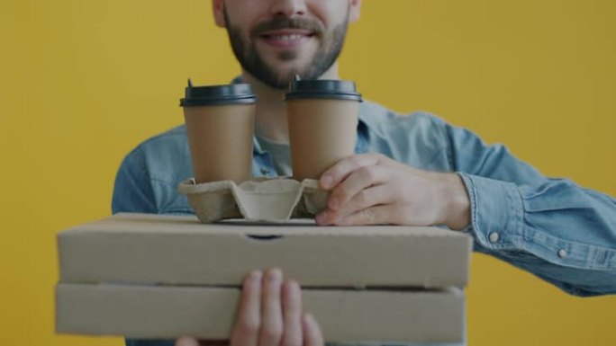 纸板箱中的披萨特写镜头，并在黄色背景上用男性手送咖啡