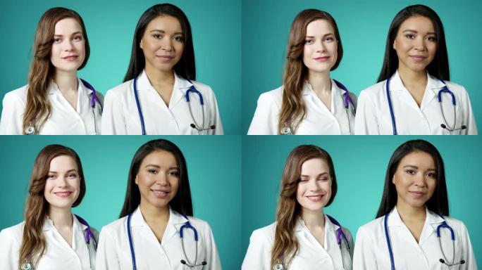 美丽年轻快乐的医务女孩对着镜头微笑。两位成功自信的现代女医生穿着白大褂慢动作摆姿势。女性医学工作者。