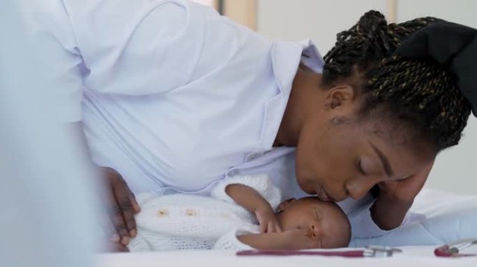 非洲民族的女医生儿科医生在医院或家里亲吻新生儿。怀孕/出生概念。