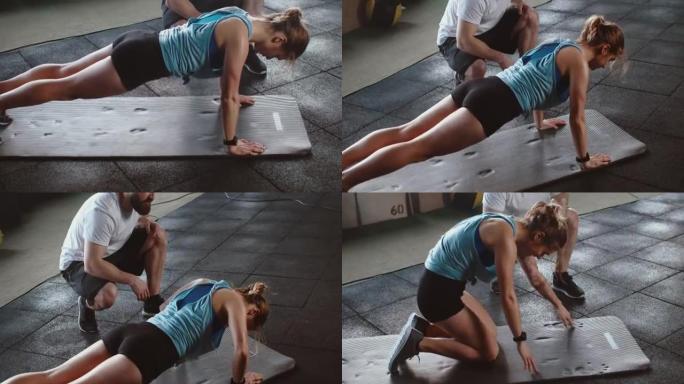 美丽的年轻苗条的白人运动女子在专业男教练的观看下在健身房垫子上做俯卧撑锻炼。