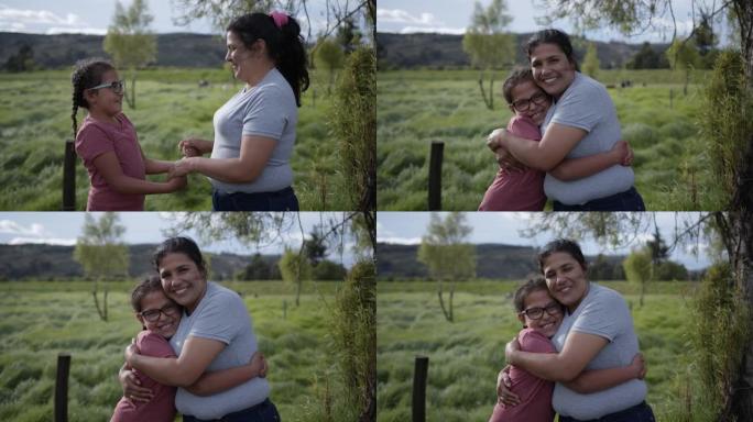 美丽甜美的女儿和母亲互相看着对方，然后在拥抱农田时对着镜头微笑