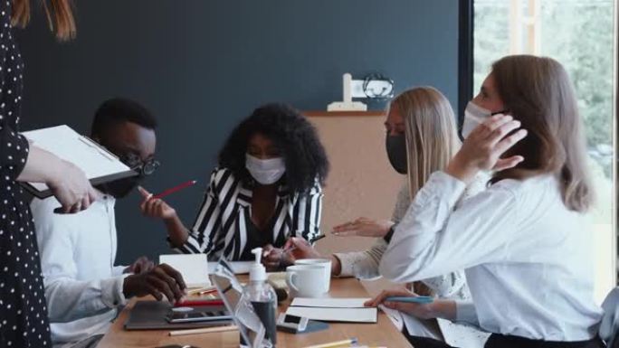 锁定后的创意商务会议。快乐的多民族合作伙伴在戴口罩的轻型办公室咨询客户。