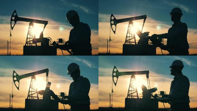 油田里一台笔记本电脑的石油工业工人的剪影