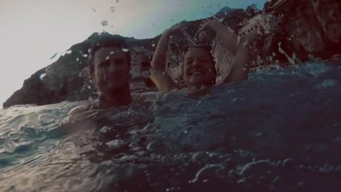 SLO MO年轻夫妇在著名村庄Positano的海湾里游泳很开心