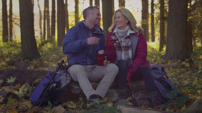 成熟的夫妇在秋天或冬天的乡村散步时停下来休息和喝热饮