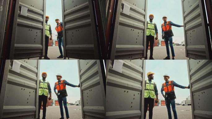 英俊的工业工程师和非裔美国人主管，戴着安全帽和安全背心，在物流码头打开一个货运集装箱。打开门时，两个