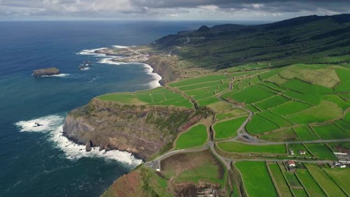 葡萄牙亚速尔群岛圣米格尔岛。飞越一个有绿色田野的农场。大西洋陡峭的海岸。多云的地平线。空中射击，UH