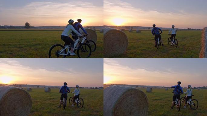 SLO MO几个骑自行车的人停下来欣赏干草中的日落美景