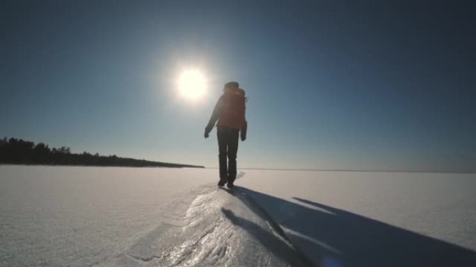 运动的女人背着背包穿过雪场。慢动作