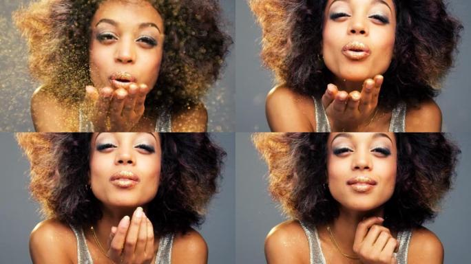 4k视频片段，一名妇女在工作室背景下从手中吹出庆祝的闪光