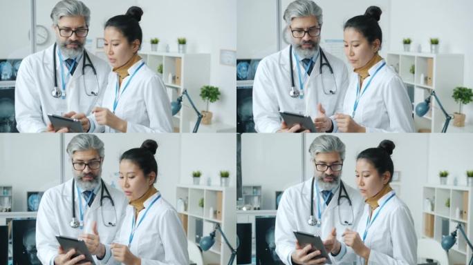医生高加索男人和亚洲女人在医院办公室里聊天和看着笔记本电脑屏幕