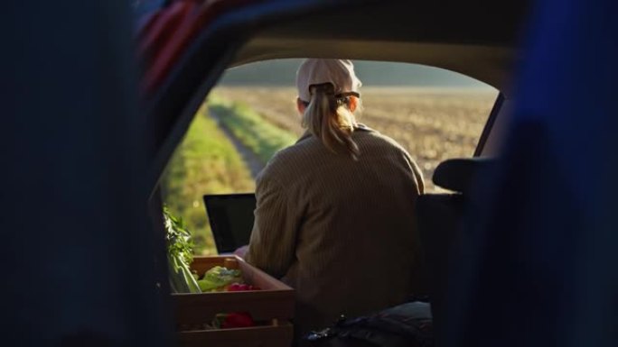 女农民收获了蔬菜，在车后的笔记本电脑上工作