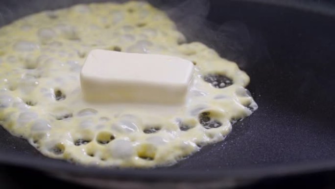 黄油在炉子上的煎锅里融化嘶嘶作响。特写。