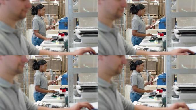 女人站在办公桌前，在仓库的计算机上工作着一张纸