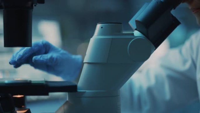 在生物应用科学实验室的显微镜下进行DNA实验的医学研究科学家的特写肖像。穿着白大褂的漂亮女实验室工程