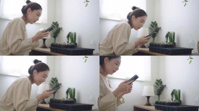 年轻女子在家用智能手机给仙人掌盆栽拍照。