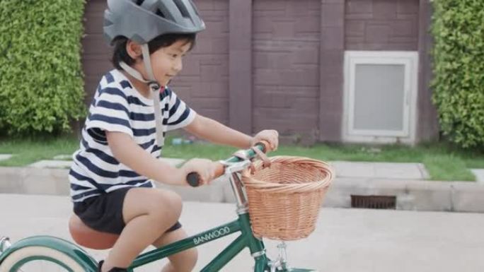 儿童男孩在道路上骑自行车。