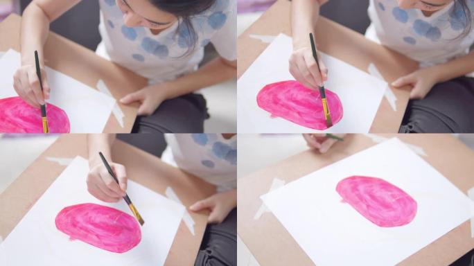 特写亚洲少女在家时在客厅绘画和绘画她的艺术和工艺。她用水彩和画笔在白纸上创作艺术作品，形成了她的想象