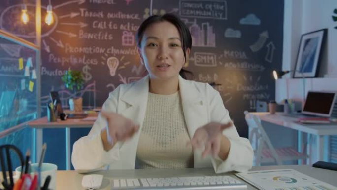亚洲企业家在创意黑暗办公室的在线视频通话中讲话和打手势