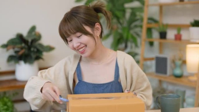 微笑的年轻亚洲女性手持智能手机在线购物，通过送货上门服务收到包裹。网上购物
