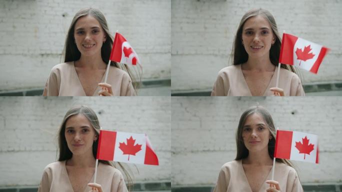 砖墙背景上户外手持加拿大国旗的可爱年轻女学生慢动作肖像