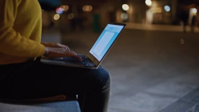 DS年轻黑人妇女晚上在城市使用笔记本电脑